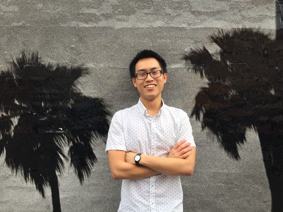 A photo of the author, Ky-Cuong Huynh, in a white t-shirt against a gray wall with monotone photos of palm trees.